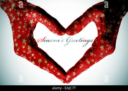 Hände mit goldenen Weihnachtssterne bilden ein Herz und der Satz Seasons Greetings gemustert Stockfoto