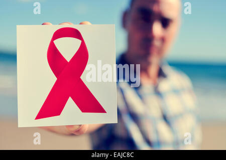 ein junger Mann zeigt ein Bild von einem roten Band für den Kampf gegen AIDS Stockfoto