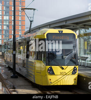 Eine gelbe Metrolink-Straßenbahn hochgezogen auf einer Plattform vor der Abreise zu Manchester Piccadilly. Stockfoto