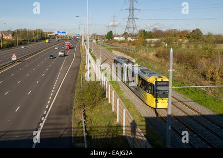 Metrolink tram neben Autobahn M60 auf der Flughafen-Linie, Manchester, England, UK Stockfoto