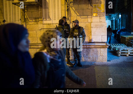 (141116)--JERUSALEM, 16. November 2014 (Xinhua)--israelische Polizisten Wache stehen als arabische Frauen Spaziergang vorbei an der Szene, wo ein jüdischer Mann im Zentrum von Jerusalem, am 16. November 2014 erstochen wurde. Ein jüdischer Mann im Zentrum von Jerusalem Sonntagabend in einem scheinbaren militante Angriff erstochen wurde, sagte Polizei-Sprecher Mickey Rosenfeld Xinhua. Das Opfer in seinen frühen dreißiger Jahren, wurde auf der Rückseite mit einem Schraubenzieher erstochen und gelitten moderate Wunden in Hanevi'im Straße im Zentrum von Jerusalem. Er wurde in der Sha'are Tzedek Medical Center in die Stadt gebracht. Der Verdächtige ist zu groß und die Polizei haben Straßensperren errichtet Stockfoto