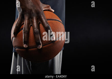 Nahaufnahme einer Hand der Basketball-Spieler mit einem Ball auf schwarzem Hintergrund. Stockfoto