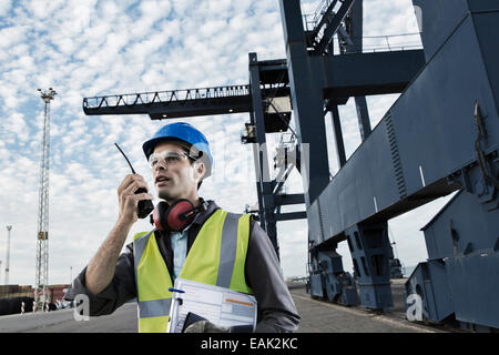 Arbeiter mit Walkie-talkie in der Nähe von Kran Stockfoto