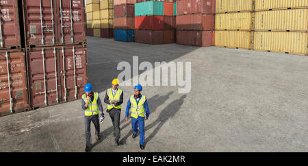 Unternehmer und Arbeitnehmer, die zu Fuß in der Nähe von Containern Stockfoto