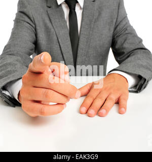 Mann in einem Anzug sitzt in einer Tabelle zeigen mit dem Finger auf den Betrachter Stockfoto