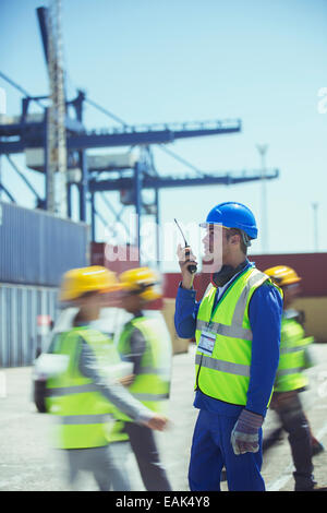 Arbeiter mit Walkie-talkie in der Nähe von Containern Stockfoto