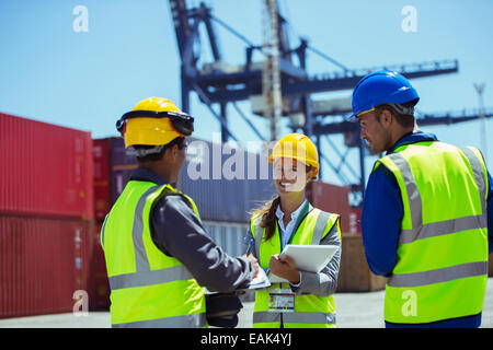 Geschäftsleute und Arbeiter in der Nähe von Containern im Gespräch Stockfoto