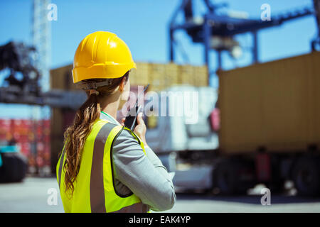 Geschäftsfrau mit Walkie-talkie in der Nähe von Containern Stockfoto