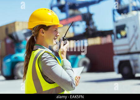 Geschäftsfrau mit Walkie-talkie in der Nähe von Container und LKW Stockfoto