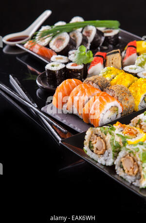 Verschiedene Arten von Sushi Essen serviert auf schwarzem Hintergrund Stockfoto