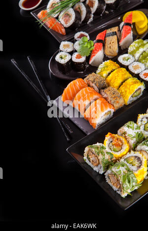 Verschiedene Arten von Sushi Essen serviert auf schwarzem Hintergrund Stockfoto