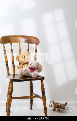 Zwei Teddybären sitzend auf einem Stuhl mit Sonnenlicht durchströmen Stockfoto