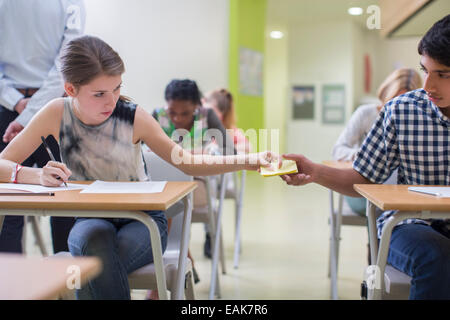 Studenten vorbei Hinweis zwischen Schreibtische bei GCSE Prüfung Stockfoto