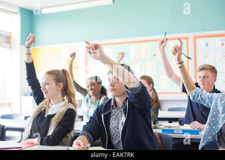 Studenten, die Erhöhung der Arme während der Lektion im Klassenzimmer Stockfoto