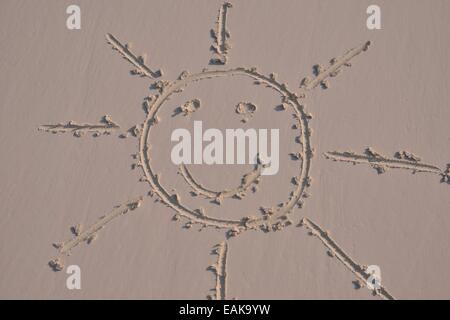Sonnengesicht in den Sand gezeichnet Stockfoto