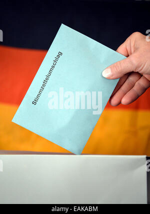 Symbolisches Bild, Wahl zum Bundestag, Hand setzen einen Umschlag Stimmzettel in eine Wahlurne vor der Flagge Deutschlands Stockfoto