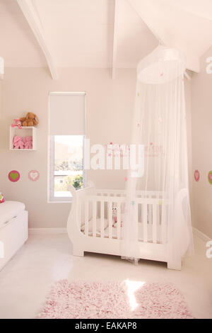 Krippe mit Tüll Baldachin in Pastell farbigen Babyzimmer weiß Stockfoto