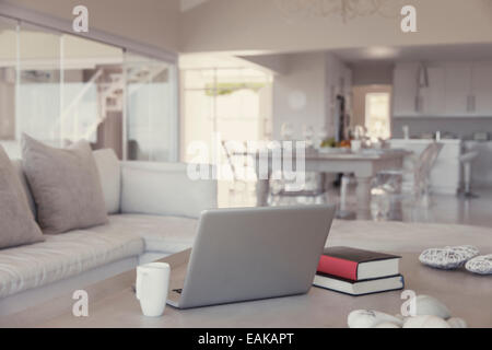 Moderne Wohnzimmer Interieur mit Laptop, Bücher und Becher auf Tisch Stockfoto