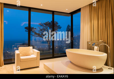 Blick auf luxuriöses Badezimmer mit Badewanne und Sessel in der Nacht Stockfoto