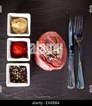 Stück rot rohes Fleisch Steak mit Kräutern, serviert auf schwarzem Steinoberfläche. Erschossen von oben betrachtet. Stockfoto