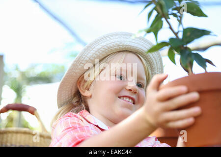 Mädchen mit Strohhut Holding Topfpflanze Stockfoto