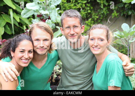 Porträt von vier Männern und Frauen tragen grüne T-shirts im Garten Stockfoto