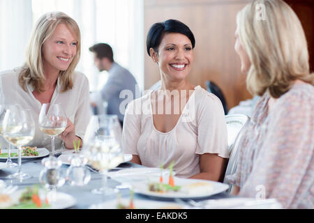 Fröhliche Frauen im Restaurant Mann im Hintergrund Stockfoto