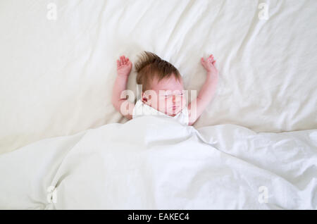 Kleine vier Wochen altes neugeborenes Mädchen schlafen in einem großen Bett Stockfoto