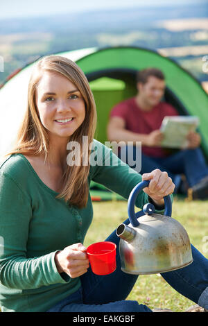 Paar machen Heißgetränk, während In Natur Camping Stockfoto