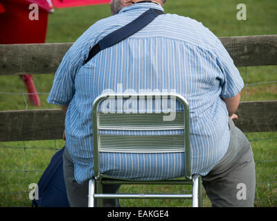 übergewichtigen Mann saß auf einem kleinen Stuhl Stockfoto