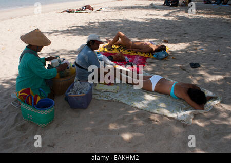 Indonesien, Bali, Kuta, Strand, Frau Essen Massage.  Sonnenbad am Strand von Kuta. Surfunterricht. Bali. Kuta ist eine Küstenstadt ich Stockfoto