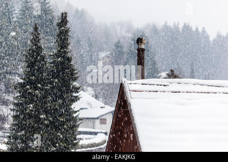 Detail eines Daches bedeckt mit Schnee mit einem Schornstein Rauchen Stockfoto