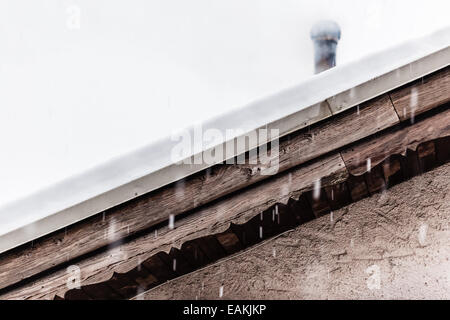 Detail eines Daches bedeckt mit Schnee mit einem Schornstein Rauchen Stockfoto