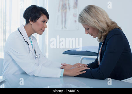 Ärztin, trösten traurige Frau am Schreibtisch im Büro Stockfoto