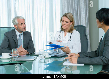 Ärztin, Mann und Frau im Gespräch am Tisch im Konferenzraum