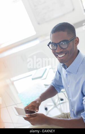 Porträt von lächelnden jungen Geschäftsmann mit Smartphone im Büro Stockfoto