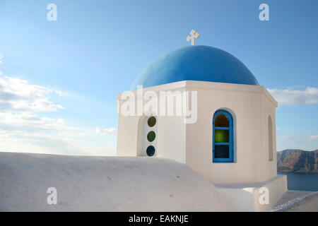 Traditionelle weiße Kirche mit einer blauen Kuppel thront auf der Seite der Klippe, Oia, Santorini, Kykladen, Griechenland. Stockfoto
