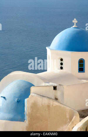 Traditionelle weiße Kirche mit einer blauen Kuppel thront auf der Seite der Klippe, Oia, Santorini, Kykladen, Griechenland. Stockfoto