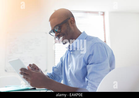 Lächelnd jungen Geschäftsmann Brillen-und blaues Hemd mit digital-Tablette in office Stockfoto