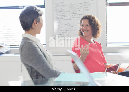 Zwei lächelnde Frauen reden in Büro, Whiteboard im Hintergrund Stockfoto