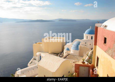 Traditionelle weiße Kirche mit einer blauen Kuppel thront auf der Seite der Klippe, Oia, Santorini, Kykladen, Griechenland. Stockfoto