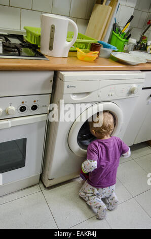 Ein kleinen Jungen (ca. 18 Monate alt) Uhren Wäsche in der Waschmaschine gewaschen werden. Stockfoto