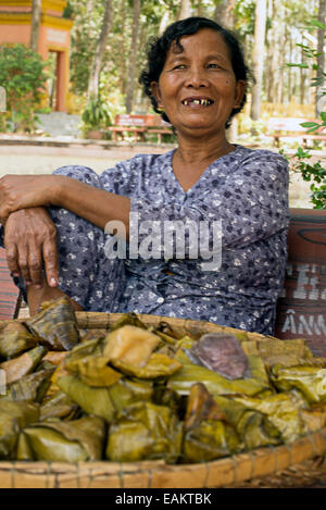Weibliche Anbieter verkaufen gefüllte Banane Blätter als eine Behandlung in der Wat Ang buddhistischen Kloster in Tra Vinh, Vietnam. Stockfoto
