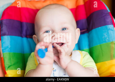 Entzückende Baby Essen im Hochstuhl. Babys erste feste Nahrung Stockfoto