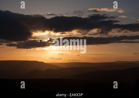 Schöner Sonnenuntergang gesehen aus Stanage Edge im Peak District, Derbyshire. Die Sonne versteckt sich hinter einer Wolke. Stockfoto