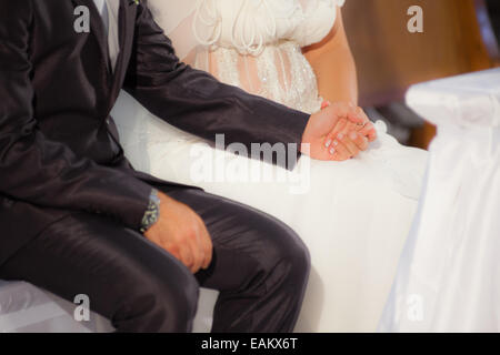 Braut und Bräutigam halten einander die Hände während der Hochzeit Stockfoto