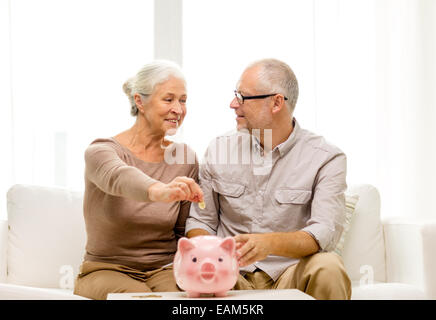 Älteres Paar mit Geld und Sparschwein zu Hause Stockfoto