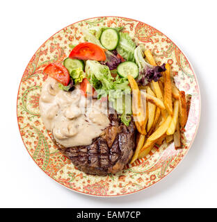 Vogelperspektive des gegrillten Ribeye Rindersteak mit Pilzsauce, Salat und Pommes frites serviert. Stockfoto