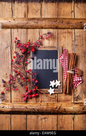 Vintage Weihnachten Hintergrund mit Kreide an Bord, Zweig mit roten Beeren, Weihnachten Plätzchen und Zimtstangen Stockfoto