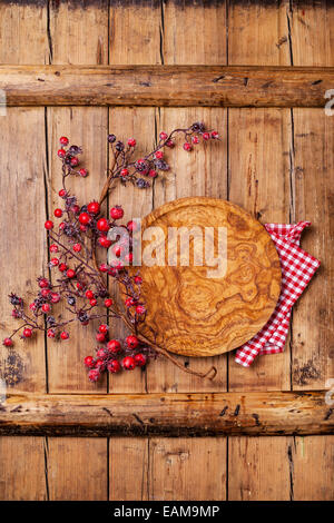 Runde Platte und Zweig mit roten Beeren auf Holz Textur Hintergrund Stockfoto